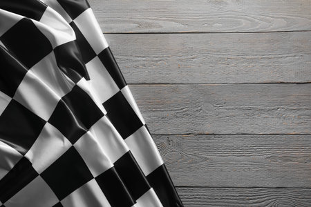 Checkered flag on grey wooden table, top view. Space for text
