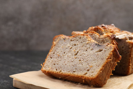 Cut banana bread with nuts on black table, closeup