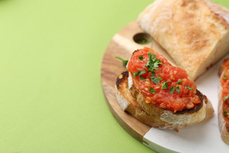 Tasty bread with tomato and parsley on green background, closeup. Space for textの写真素材