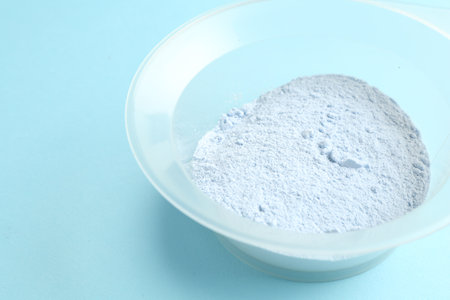 Bowl with hair bleaching powder on light blue background, closeupの写真素材