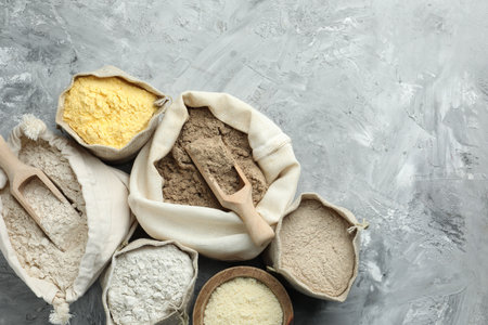 Different types of flour in bags on grey textured table, flat lay. Space for textの写真素材