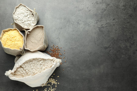 Different types of flour in bags on grey table, flat lay. Space for textの写真素材