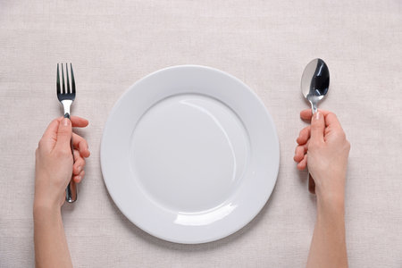 Woman with cutlery and empty plate at table, top viewの写真素材
