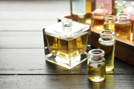 Perfume bottles with aromatic oils on black wooden background, closeupの写真素材