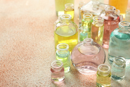 Perfume bottles with aromatic oils on beige textured background, closeup. Space for textの写真素材