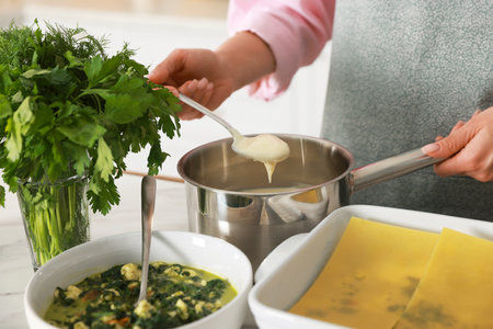 Woman making spinach lasagna at table indoors, closeupの写真素材