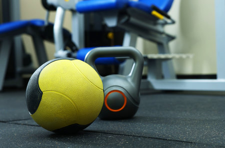 Yellow medicine ball and kettlebell on floor in gym, space for textの写真素材