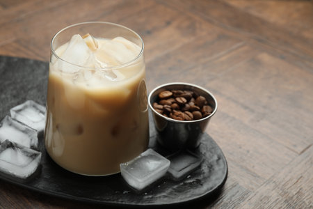 Coffee cream liqueur in glass, ice cubes and beans on wooden table, closeup. Space for textの写真素材