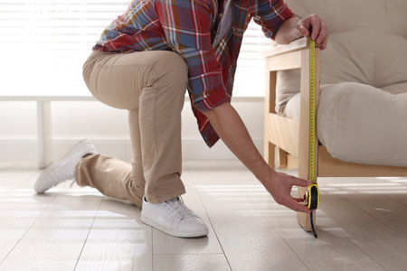 Man measuring armchair with tape indoors, closeupの写真素材