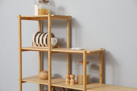 Wooden shelving unit with different home decor near light grey wall indoors
