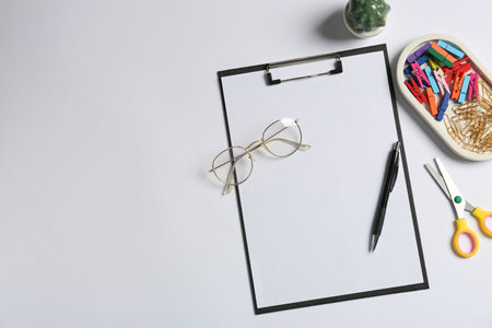 Clipboard, other stationery, decor and glasses on white background, flat lay. Space for textの写真素材