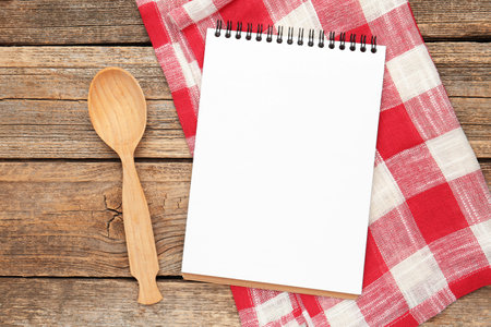 Blank recipe book, spoon and napkin on wooden table, flat layの写真素材