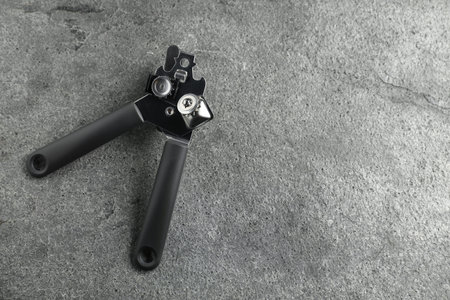One can opener on grey table, top view. Space for text