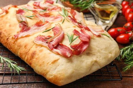 Delicious focaccia bread with bacon and rosemary on wooden table, closeupの写真素材
