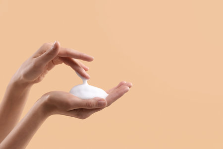 Woman washing hands with foaming soap on beige background, closeup with space for text. Hygieneの写真素材