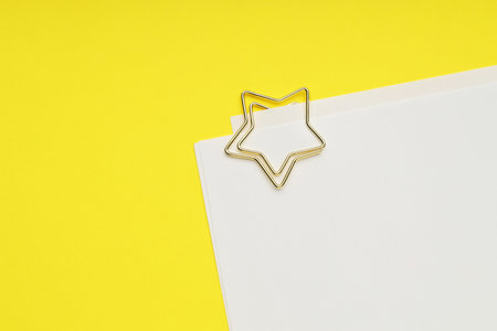 Star shaped paper clip and notes on yellow background, top view. Space for textの写真素材
