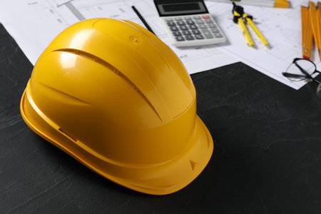 Hard hat, different engineering drawings and tools on black table, closeupの写真素材