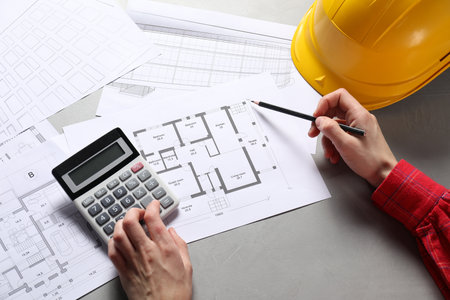Architect working with project, closeup. Different technical drawings and hard hat on gray tableの写真素材