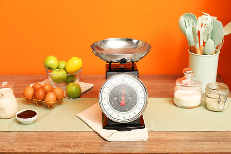 Kitchen scale, products and cooking utensils on wooden tableの写真素材