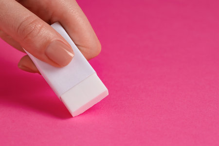 Woman using eraser on pink background, closeup. Space for textの写真素材