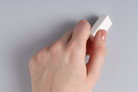 Woman using eraser on gray background, closeupの写真素材