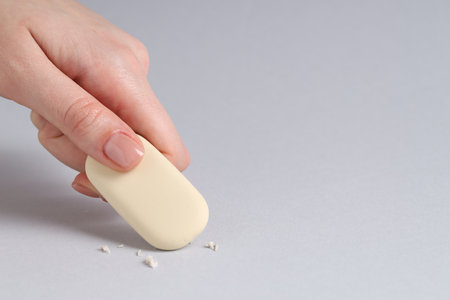 Woman using eraser on grey background, closeup. Space for textの写真素材