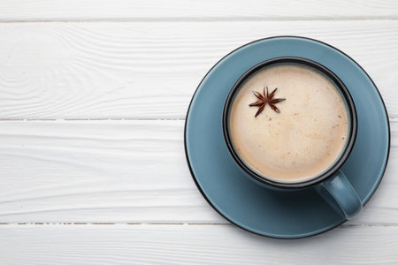 Aromatic Masala tea with anise star in cup on white wooden table, top view. Space for textの写真素材