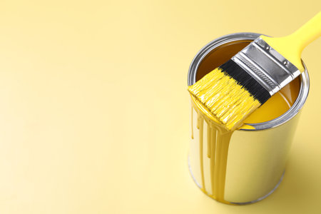 Can of paint and brush on yellow background, closeup. Space for textの写真素材