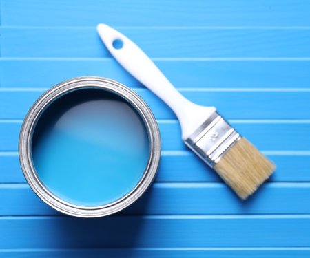 Can of bright paint and brush on light blue wooden table, flat layの写真素材