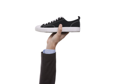 Hand holding stylish sneaker on white background, closeup