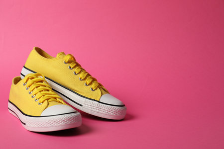Sports shoes. Yellow sneakers on pink background, space for textの写真素材
