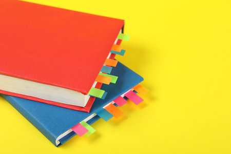 Books with colorful tabs on yellow background, closeup. Space for textの写真素材