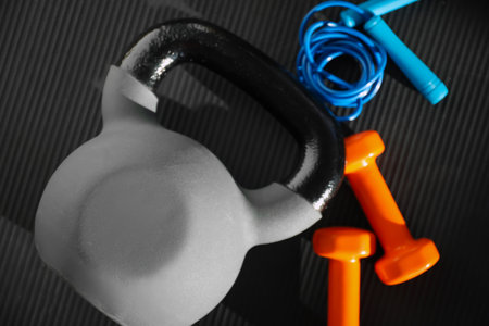 Kettlebell, jumping rope and dumbbells on fitness mat, top viewの写真素材