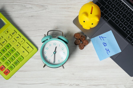 Alarm clock, coins, calculator, laptop and piggy bank on white wooden table, flat lay. Tax timeの写真素材
