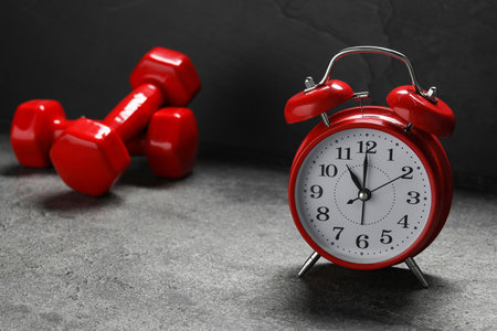 Alarm clock and dumbbells on grey backgroundの写真素材