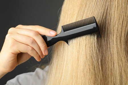 Woman brushing hair with plastic comb on gray background, closeupの写真素材