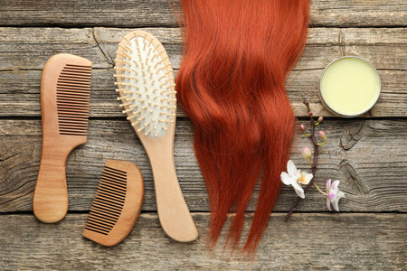 Brush, combs, wax and lock of hair on wooden table, flat layの写真素材