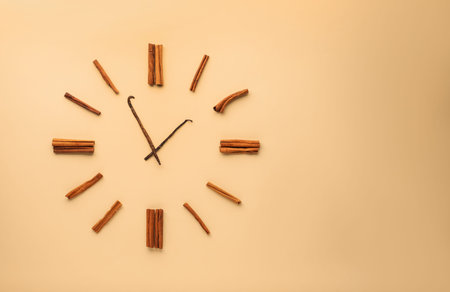 Cinnamon sticks and vanilla pods representing clock on beige background, flat lay. Space for text