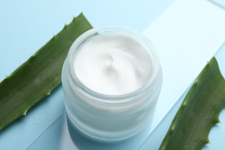 Cream and aloe leaves on light blue background, closeupの写真素材