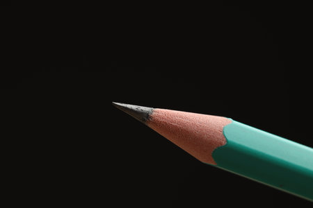 One sharp graphite pencil on black background, closeup. Space for textの写真素材