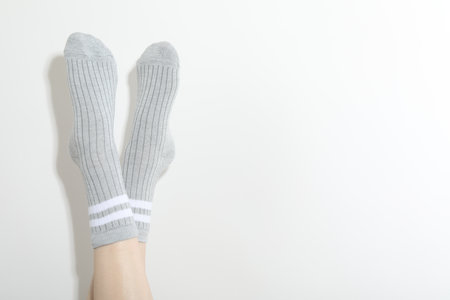 Woman in grey socks on light background, closeup. Space for textの写真素材