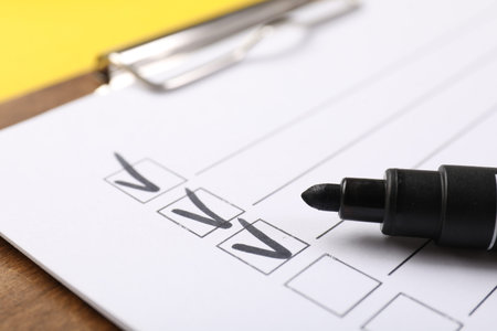 Checklist and marker on yellow background, closeup