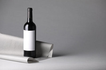 Bottle of wine and paper on gray background. Space for textの写真素材