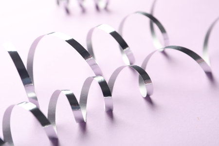 Shiny serpentine streamers on lilac background, closeupの写真素材