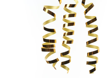 Many gold serpentine streamers on white background. Festive decorの写真素材