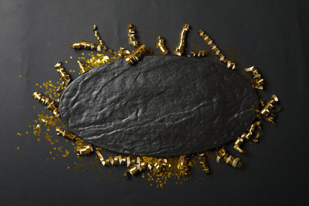 Frame of golden serpentine streamers and confetti on black background, flat lay.の写真素材