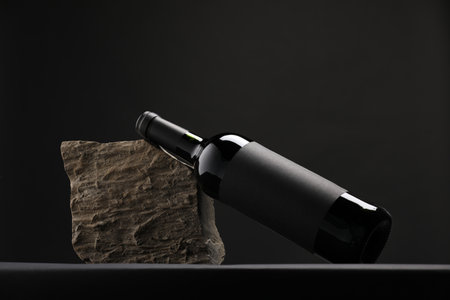 Bottle of wine and rock on black tableの写真素材