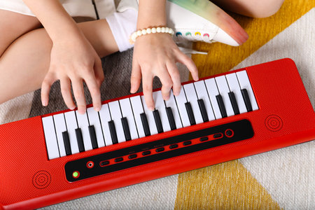 Girl playing toy piano on floor at home, closeup