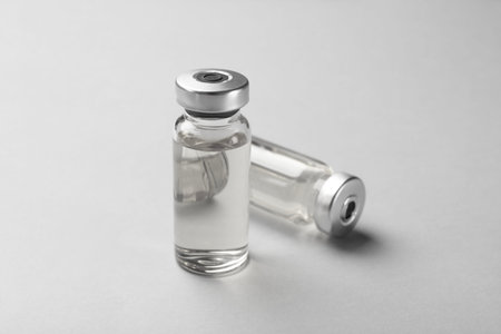 Hepatitis vaccine in glass vials on grey background, closeup