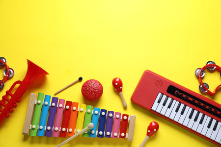 Flat lay composition with different toy musical instruments on yellow background. Space for text